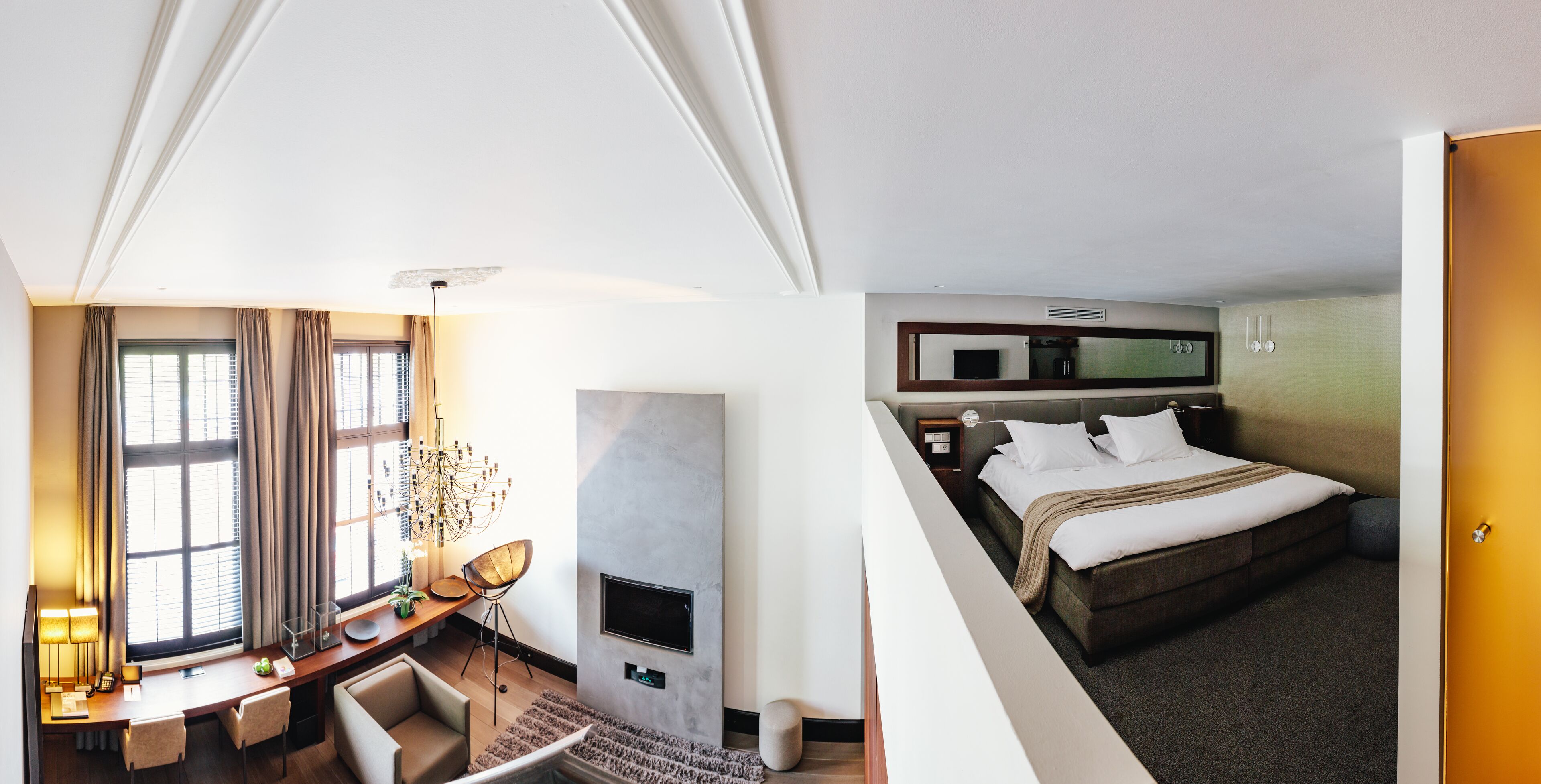 A hotel room with a desk, chair, TV, and a bed.