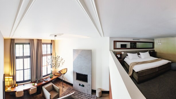 A hotel room with a desk, chair, TV, and a bed. - The Dylan Amsterdam (Amsterdam)