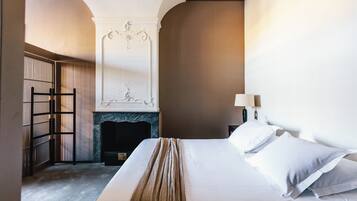 Quarto de hotel com cama, lareira, mesa de cabeceira e abajur.