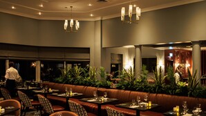 A restaurant with a long booth seating area, tables with chairs, and a bar area. - Hotel Woodstock, an Ascend Hotel Collection Member (Ennis)