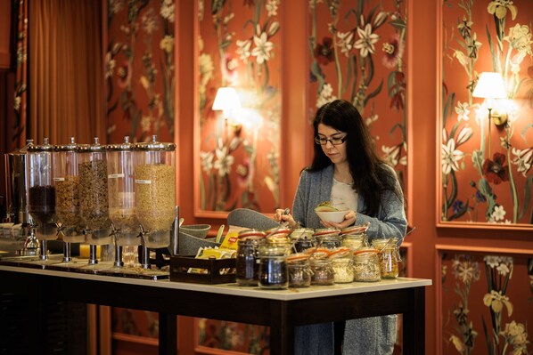 A woman at a buffet table with various food items and condiments. - Hotel Woodstock, an Ascend Hotel Collection Member (Ennis)