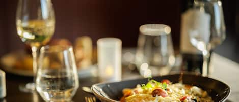 Una mesa de comedor con un cuenco de comida, copas de vino y cubiertos.
