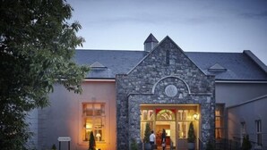 A stone building with a clock, a glass door, and a sign that reads "Hotel." - Hotel Woodstock, an Ascend Hotel Collection Member (Ennis)