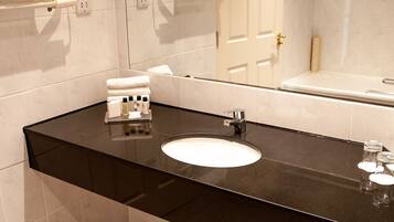 A modern bathroom with a black countertop, white sink, and a large mirror.