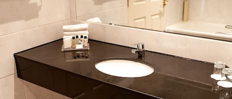 A modern bathroom with a black countertop, white sink, and a large mirror.