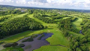 An aerial view of a golf course with multiple green areas, water bodies, and dense tree coverage. - Hotel Woodstock, an Ascend Hotel Collection Member (Ennis)