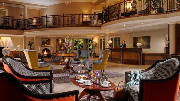 A spacious lobby with a grand chandelier, a fireplace, and a reception desk. - Hotel Woodstock, an Ascend Hotel Collection Member (Ennis)