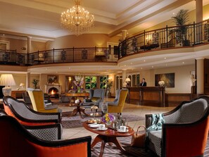 A spacious lobby with a grand chandelier, a fireplace, and a reception desk. - Hotel Woodstock, an Ascend Hotel Collection Member (Ennis)