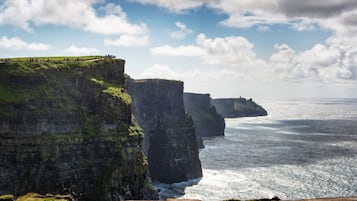 A coastal cliff with a grassy path and a view of the ocean.