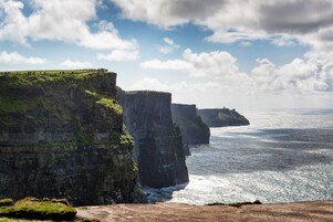 A coastal cliff with a grassy path and a view of the ocean.