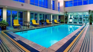 Uma grande piscina interior com cadeiras amarelas e plantas em vasos ao redor da borda.