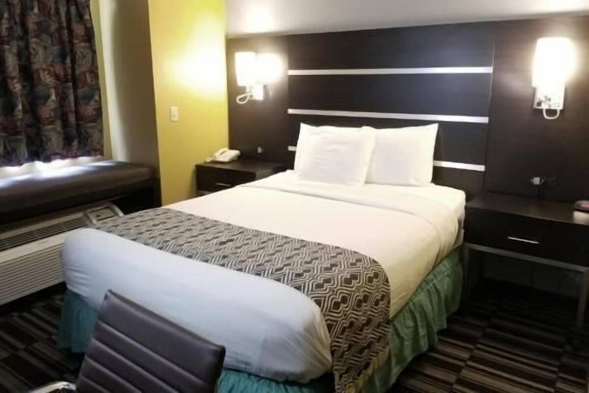 Ein Hotelzimmer mit Bett, Nachttischen, Telefon und einem Fenster mit Vorhängen.