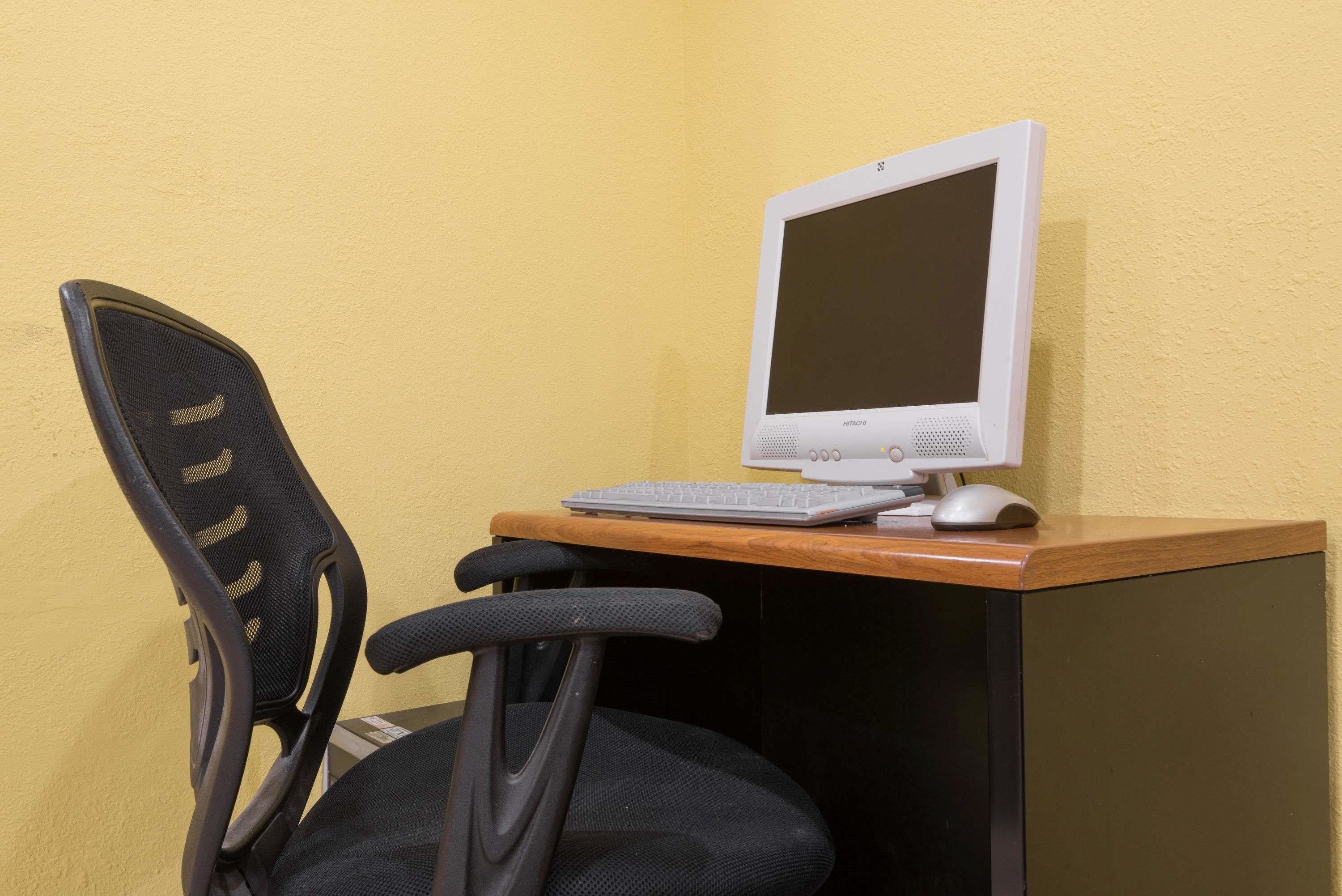 A computer desk with a monitor, keyboard, and mouse.