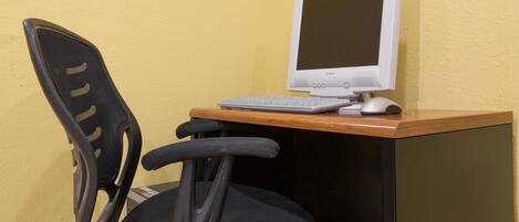 A computer desk with a monitor, keyboard, and mouse.
