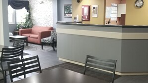 Un espace d’accueil comprenant un comptoir, un canapé, un fauteuil à motifs zébrés et un coin repas avec des chaises et une table.
