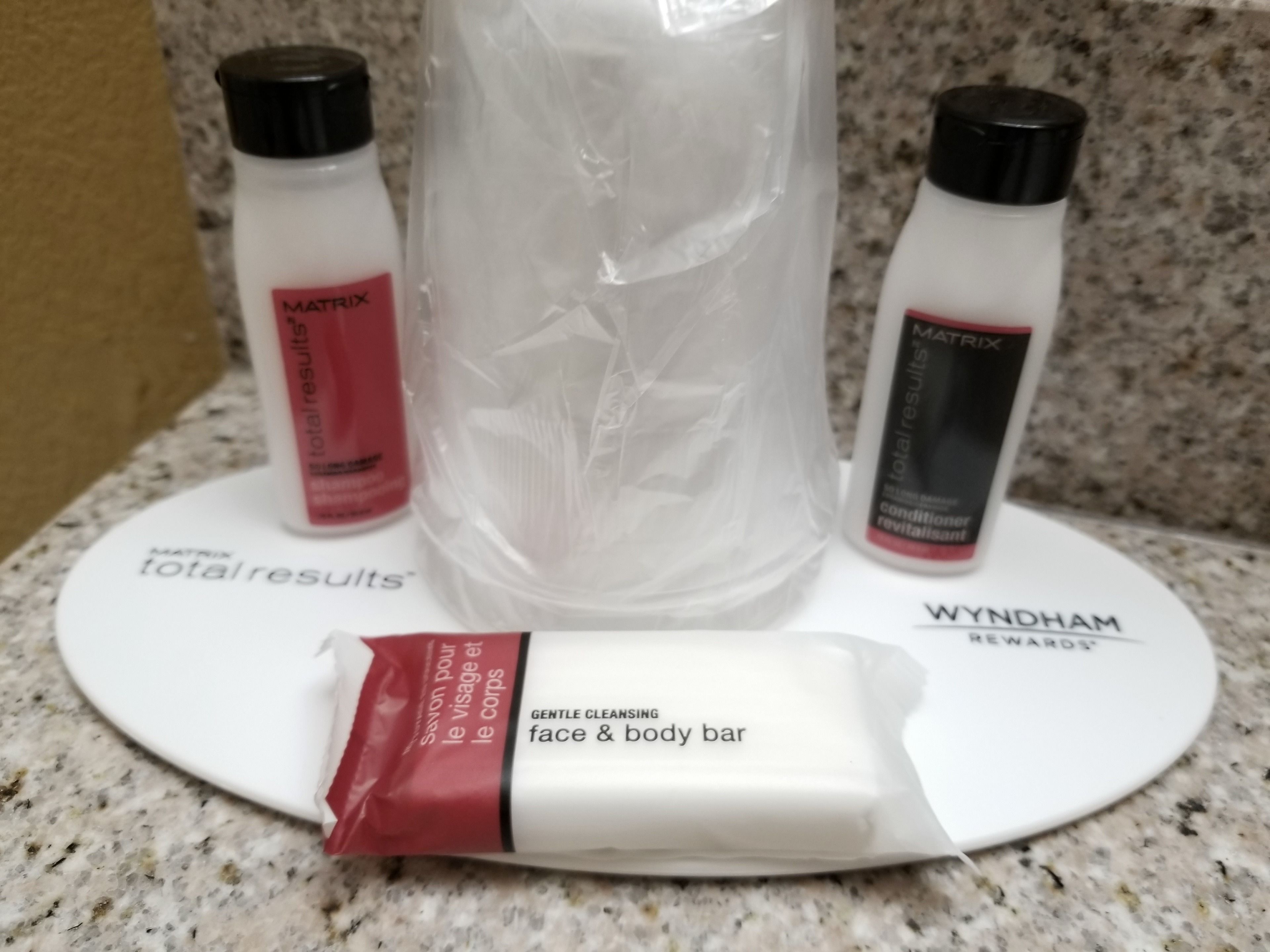 A bathroom counter with a face and body bar, two bottles of lotion, and a large bottle of water.
