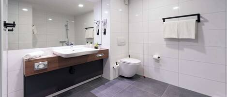 Un baño moderno con un espejo grande, un lavamanos, un inodoro y un perchero para toallas.