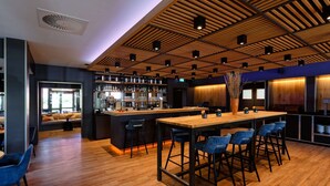 Eine moderne Bar mit Holzbalkendecke, Barhocker und einer langen Theke.