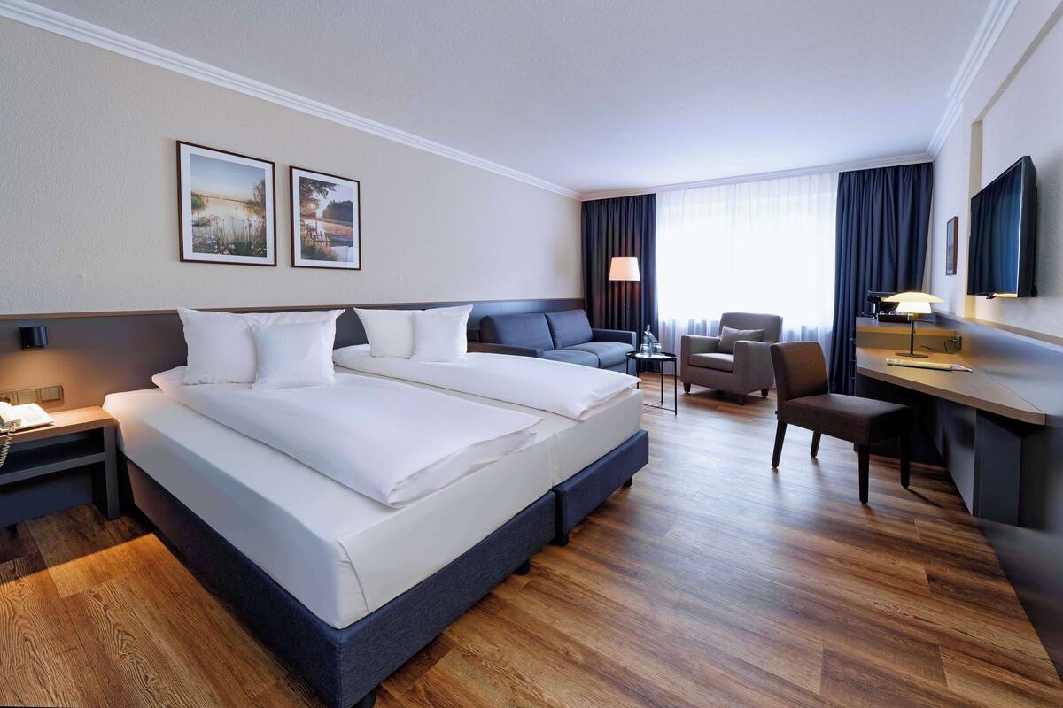 Una habitación de hotel con una cama grande, un escritorio, una silla y un televisor.