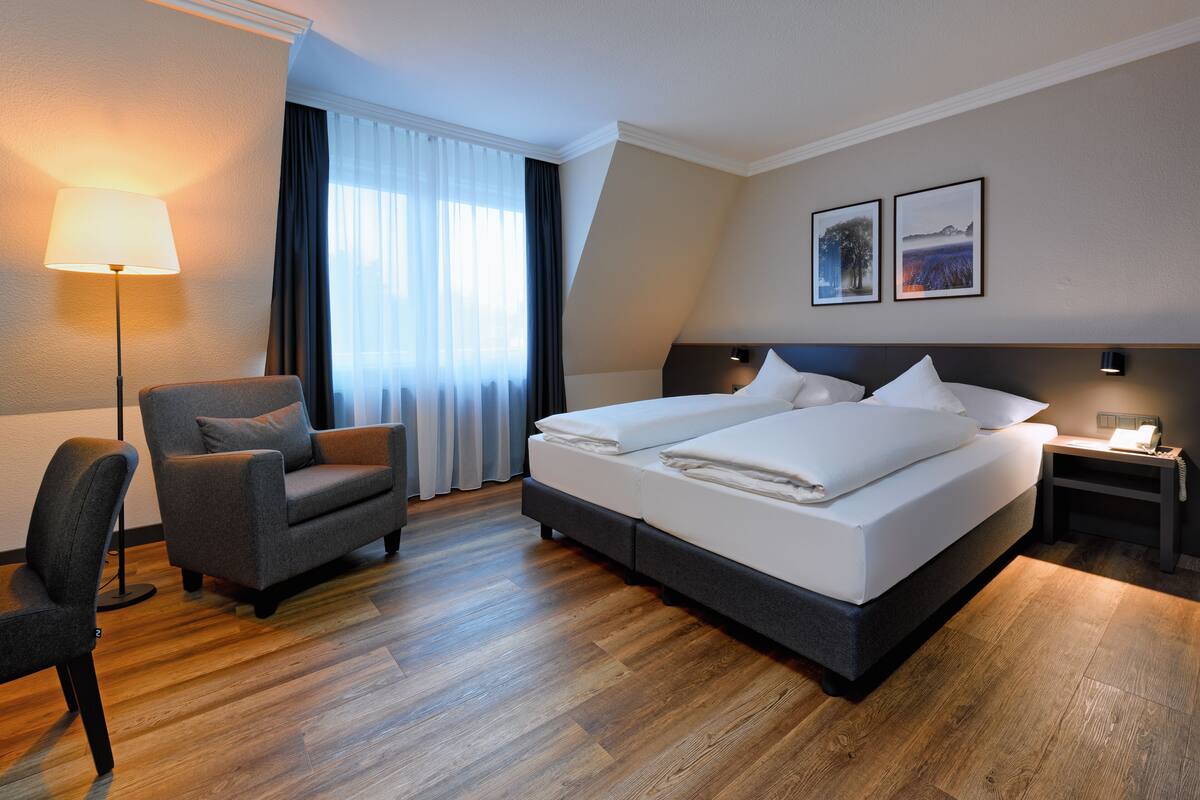 Una habitación de hotel con una cama grande, una silla, un escritorio y una lámpara.