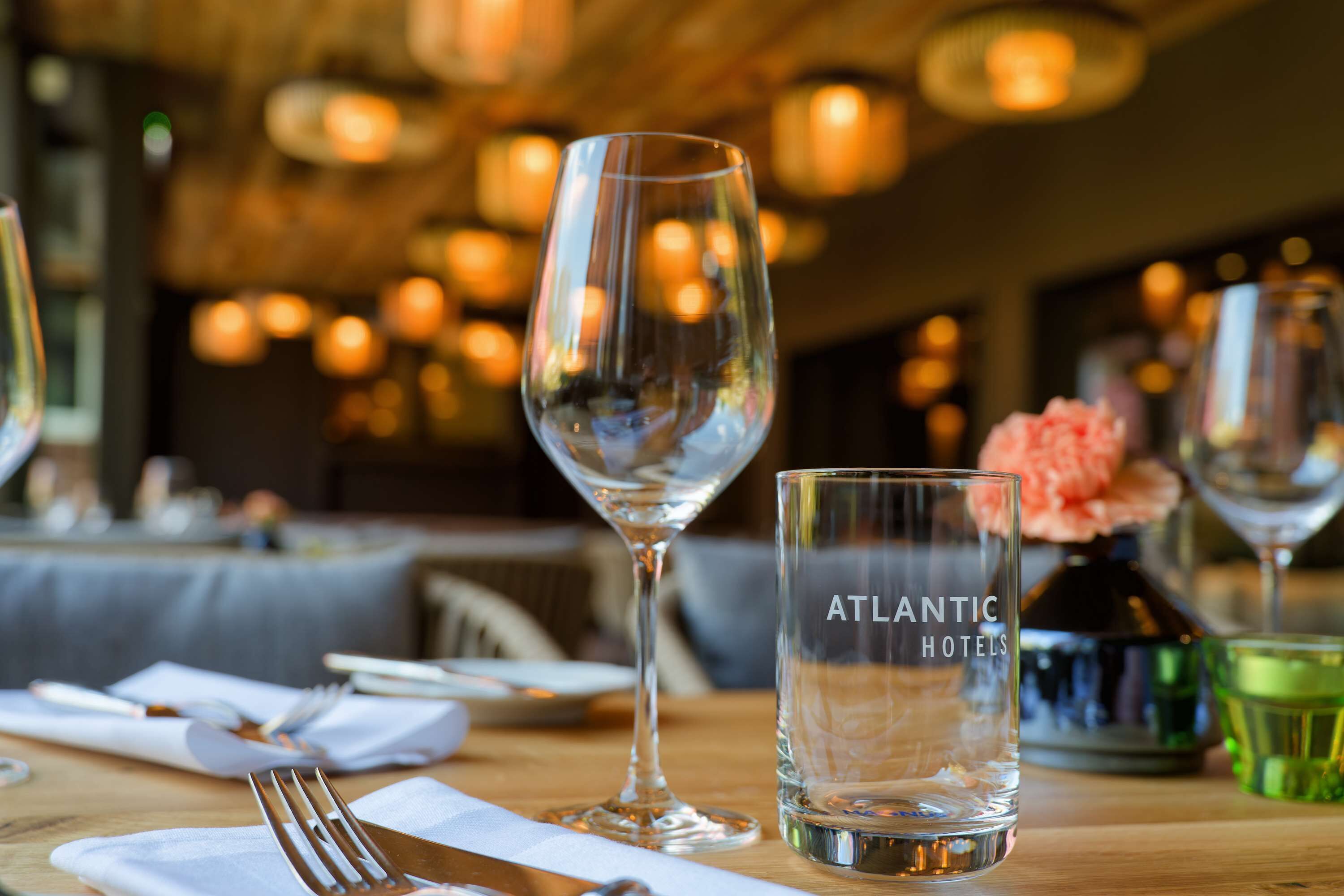 A dining table with a wine glass, a water glass, and a vase with flowers.