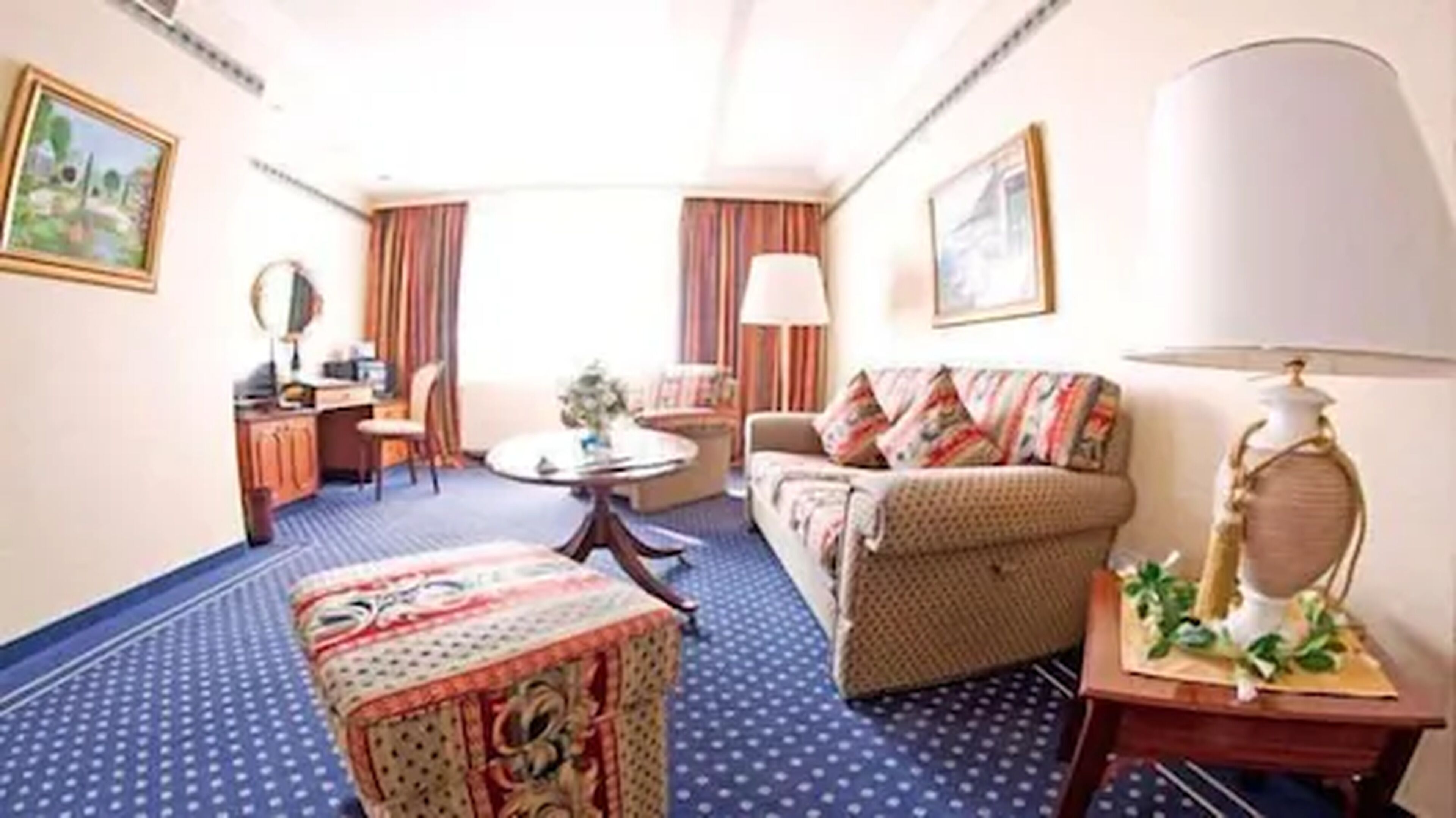 A hotel room with a sofa, a small table, a desk, and a chair.