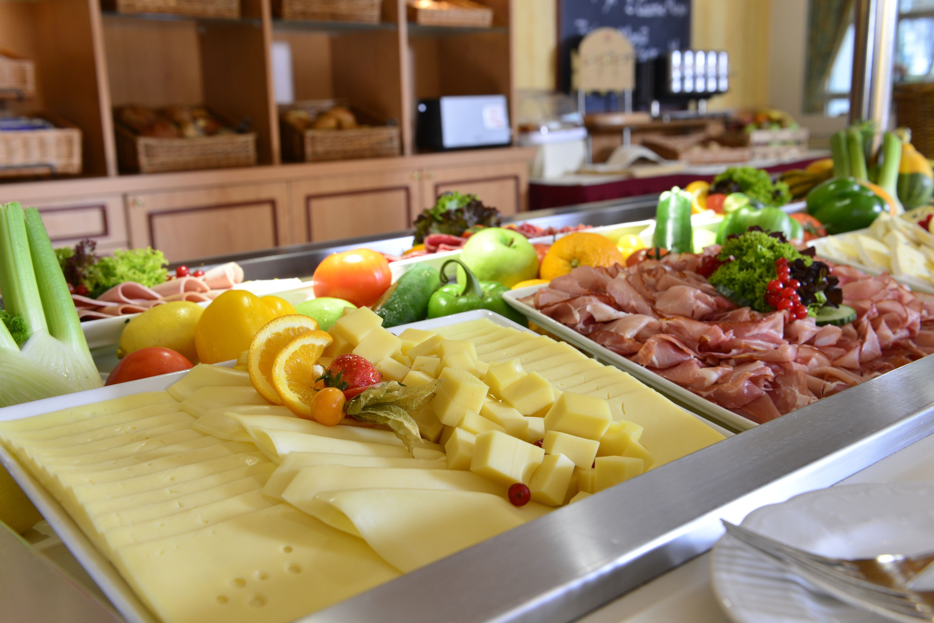 Ein Buffet mit verschiedenen Speisen, darunter Käse, Fleisch, Obst und Gemüse.