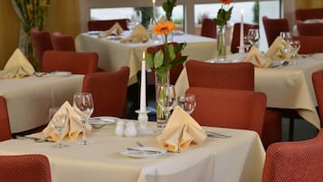 Ein Restaurant mit gedeckten Tischen, rote Stühle und weiße Tischdecken.