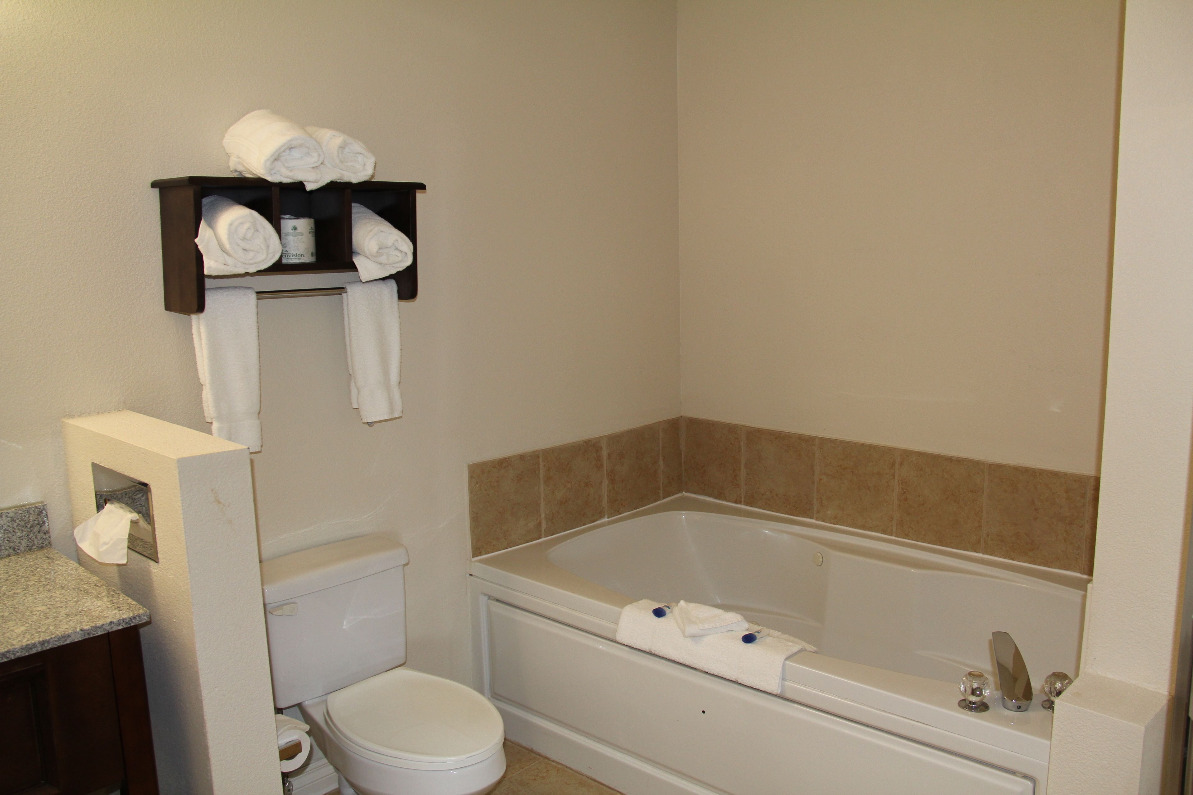 A bathroom with a toilet, a bathtub, and a shelf with towels.