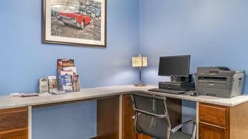 A home office with a desk, computer, printer, and framed picture on the wall.