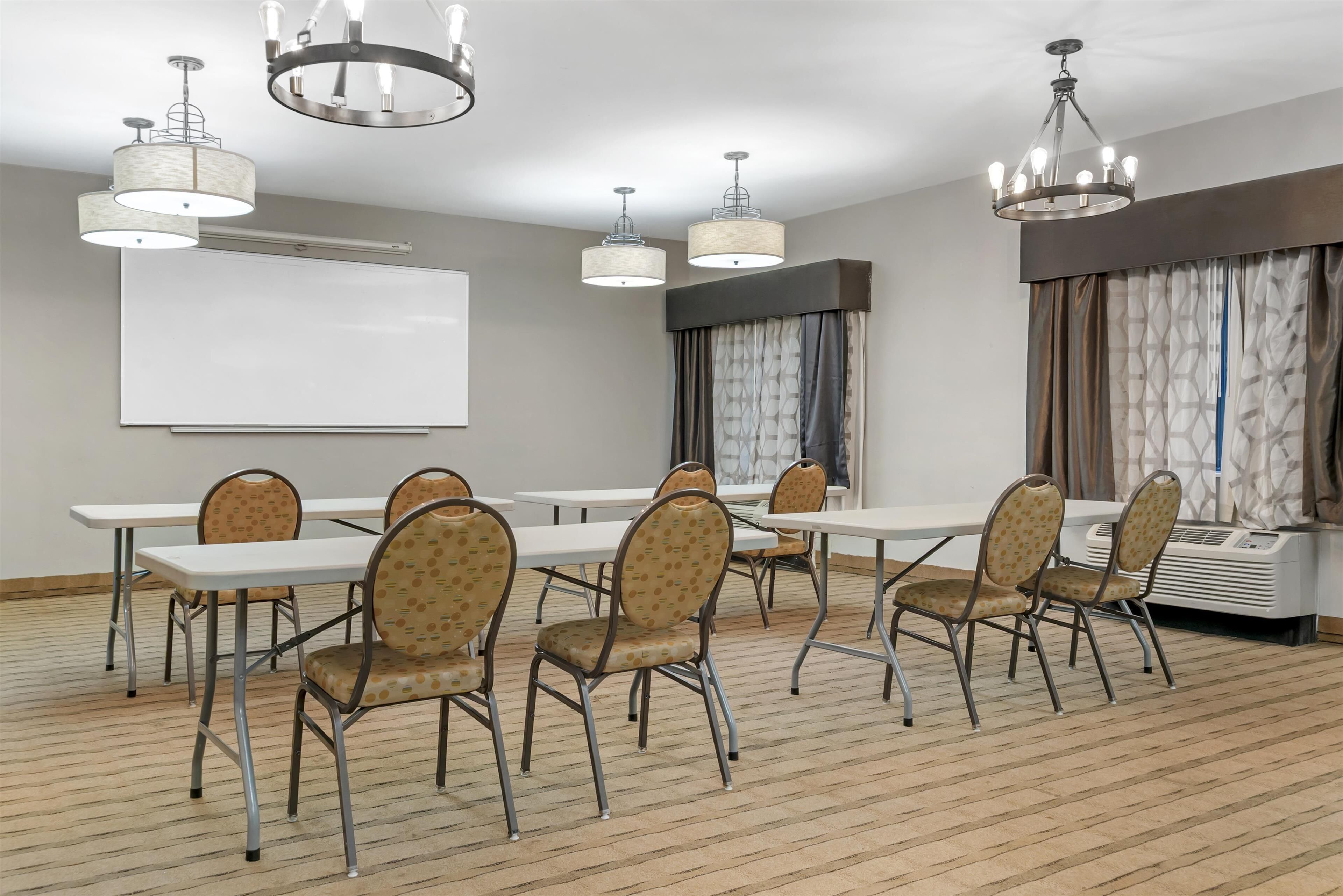 A conference room with a whiteboard, multiple tables, chairs, and a projector.
