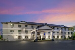 Ein mehrstöckiges Hotel mit überdachter Eingangspartie und Parkplatz.