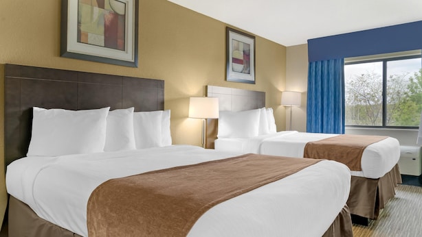 A hotel room with two beds, a large window with blue curtains, and artwork on the walls. - Best Western Port Huron Blue Water Bridge (Port Huron)