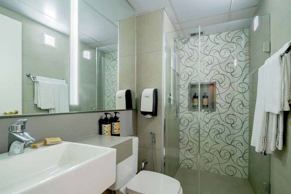 Een moderne badkamer met een wit wastafelmeubel, toilet en douchecabine met glazen wanden.