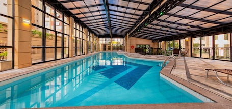 Una piscina techada, sillones reclinables de piscina