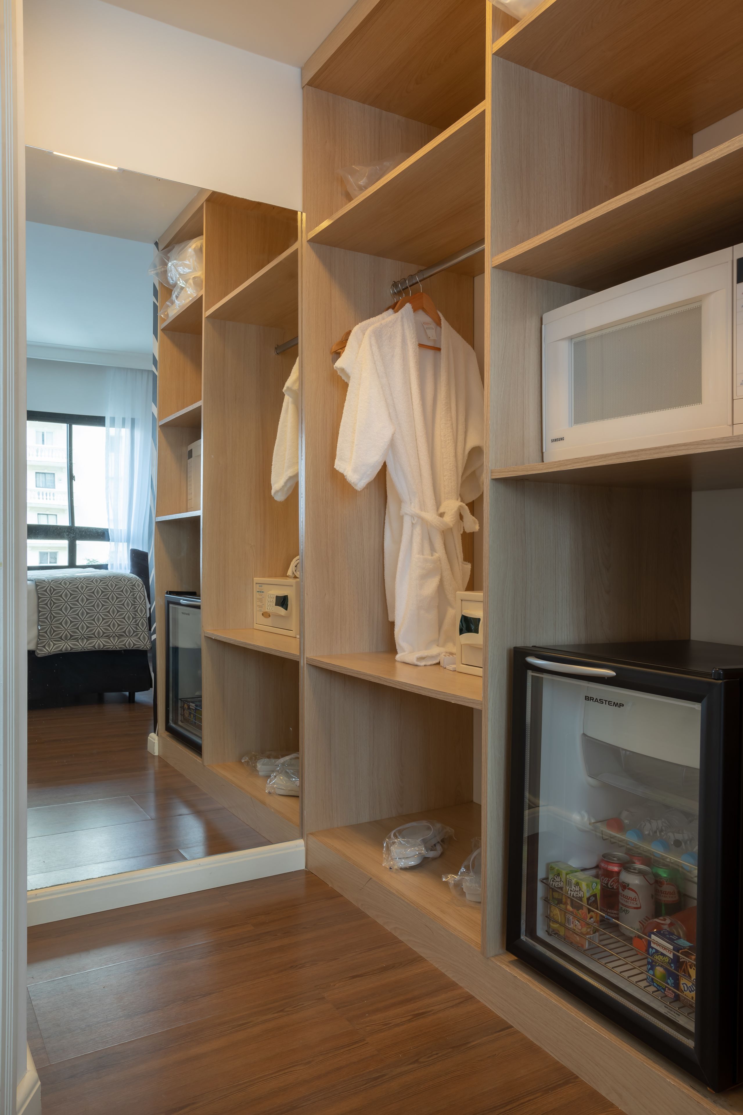 A hotel room with a walk-in closet, a bed, a minibar, and a refrigerator.