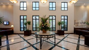 A lobby with a marble floor, a central round table with a floral arrangement, multiple windows, and leather seating areas. - Mercure Sao Paulo Pinheiros (São Paulo)
