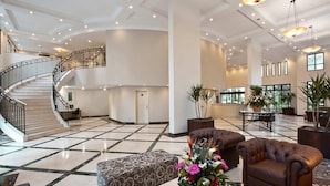 A spacious lobby with a marble floor, a staircase, leather sofas, and potted plants. - Mercure Sao Paulo Pinheiros (São Paulo)