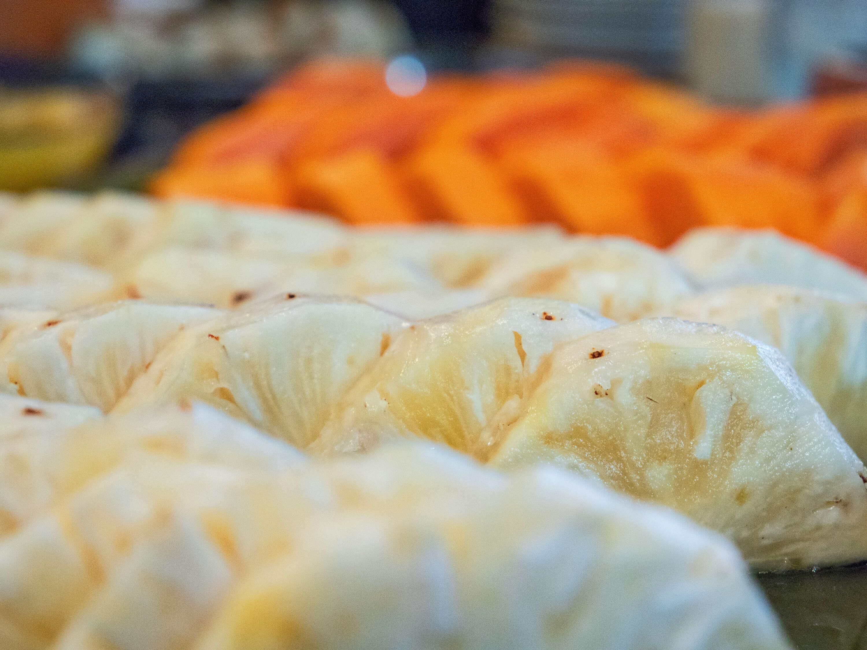 A close-up of a food item with a textured surface, possibly a pastry or baked good, with a blurred background suggesting a dining setting.
