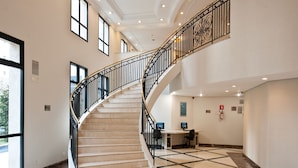 A spacious lobby with a marble floor, a curved staircase with black railings, and a reception desk with computers. - Mercure Sao Paulo Pinheiros (São Paulo)