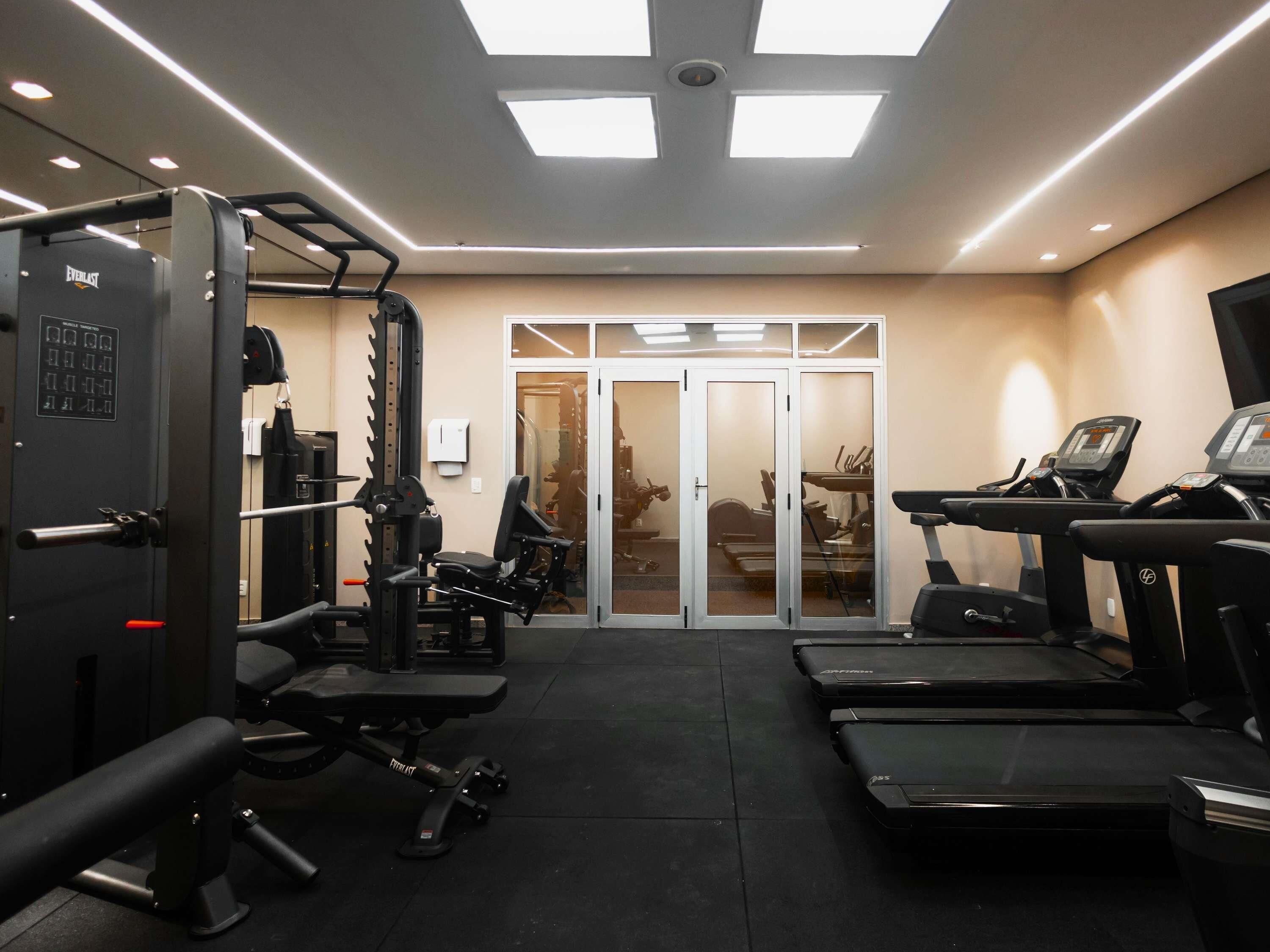 A gym with weightlifting equipment, treadmills, and a mirrored wall.