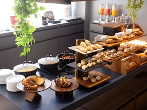 Ein Buffet mit verschiedenen Backwaren, einer Kaffeestation und einer Saftbar.