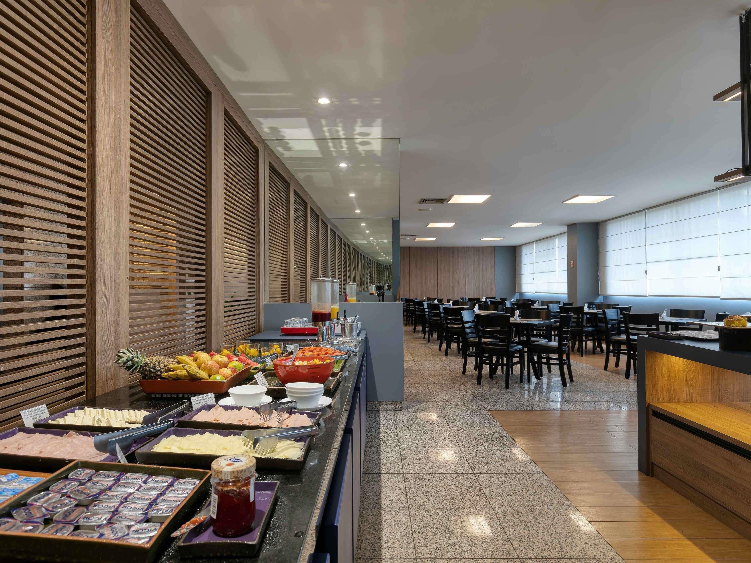 A buffet area with various food options, a seating area with tables and chairs, and a large window with blinds.