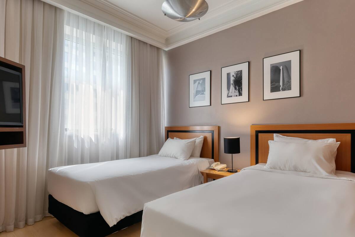 Habitación de hotel con dos camas, un televisor y tres cuadros en la pared.