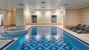 A swimming pool with a geometric tile pattern, a hot tub, and lounge chairs. - Leonardo Hotel Middlesbrough (Middlesbrough)