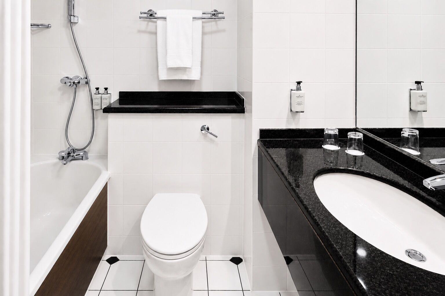 Une salle de bain moderne avec des toilettes blanches, un lavabo noir et un espace douche.