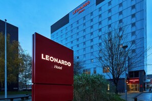 A hotel sign with the name "LEONARDO Hotel" in front of a modern building with a blue facade.