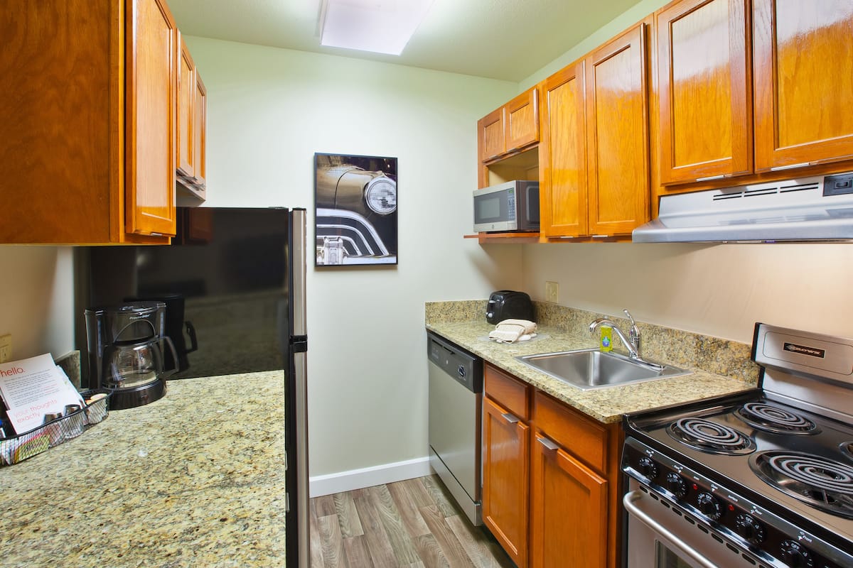 A kitchen with wooden cabinets, a microwave, a coffee maker, a dishwasher, and a stove.