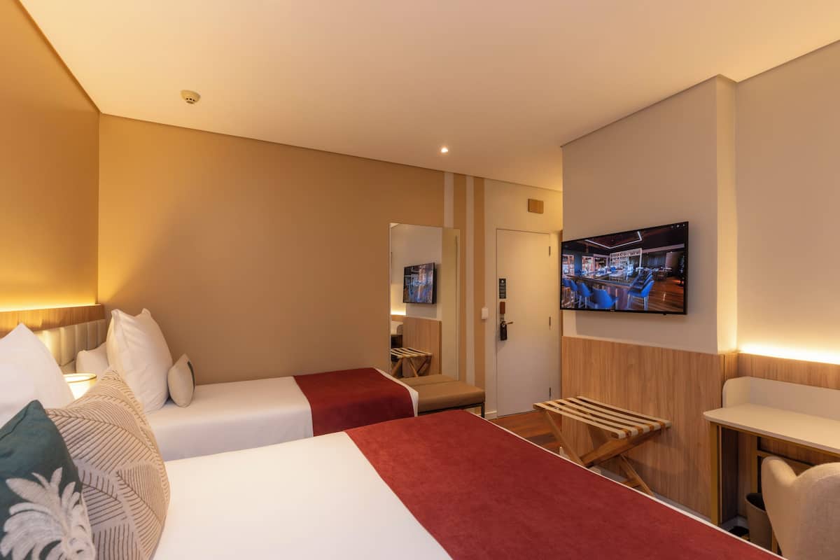 Een hotelkamer met twee bedden, een televisie, een bureau en een spiegel.