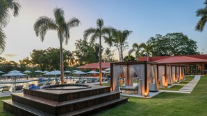 A poolside area with a hot tub, lounge chairs, and umbrellas. - Sanma Hotel  (Foz do Iguaçu)